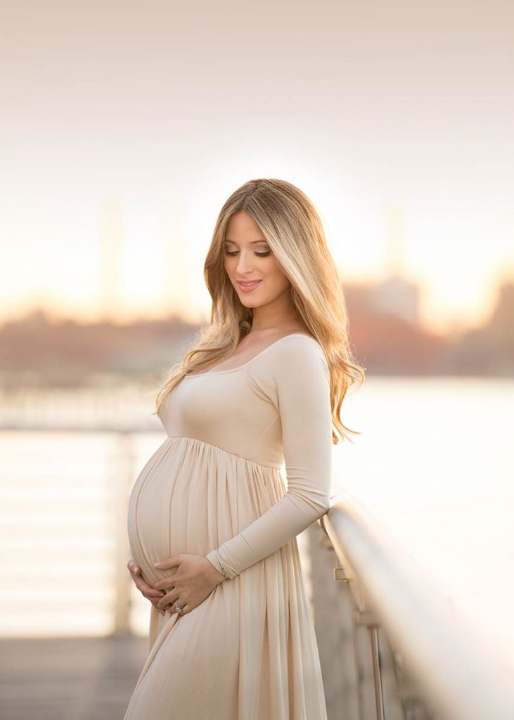 Closeup of a young pregnant woman posing near the East River during sunset.