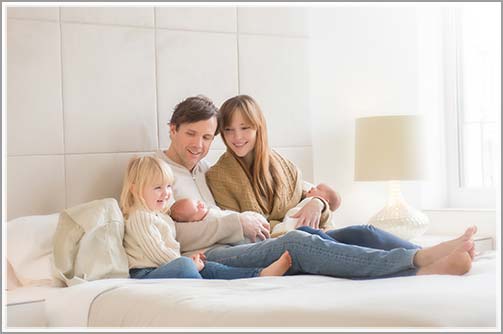 Lifestyle photo of a family with a newborn baby on bed
