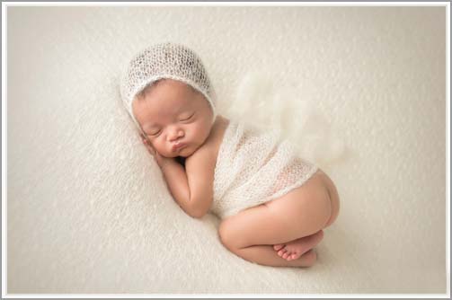 Portrait of a newborn baby with a wrap on white blanket