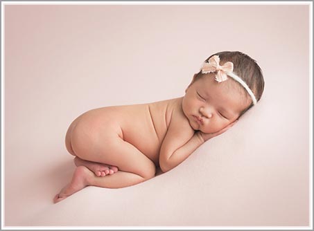 Portrait of a newborn baby with a wrap on white blanket