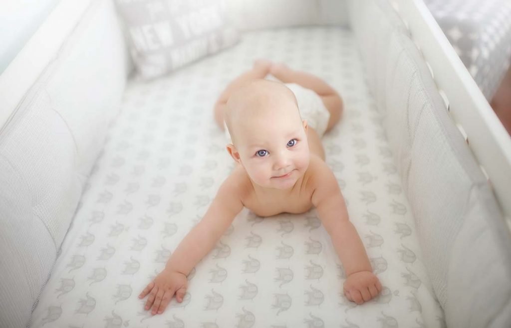 Young baby laying happily in crib and smiling.