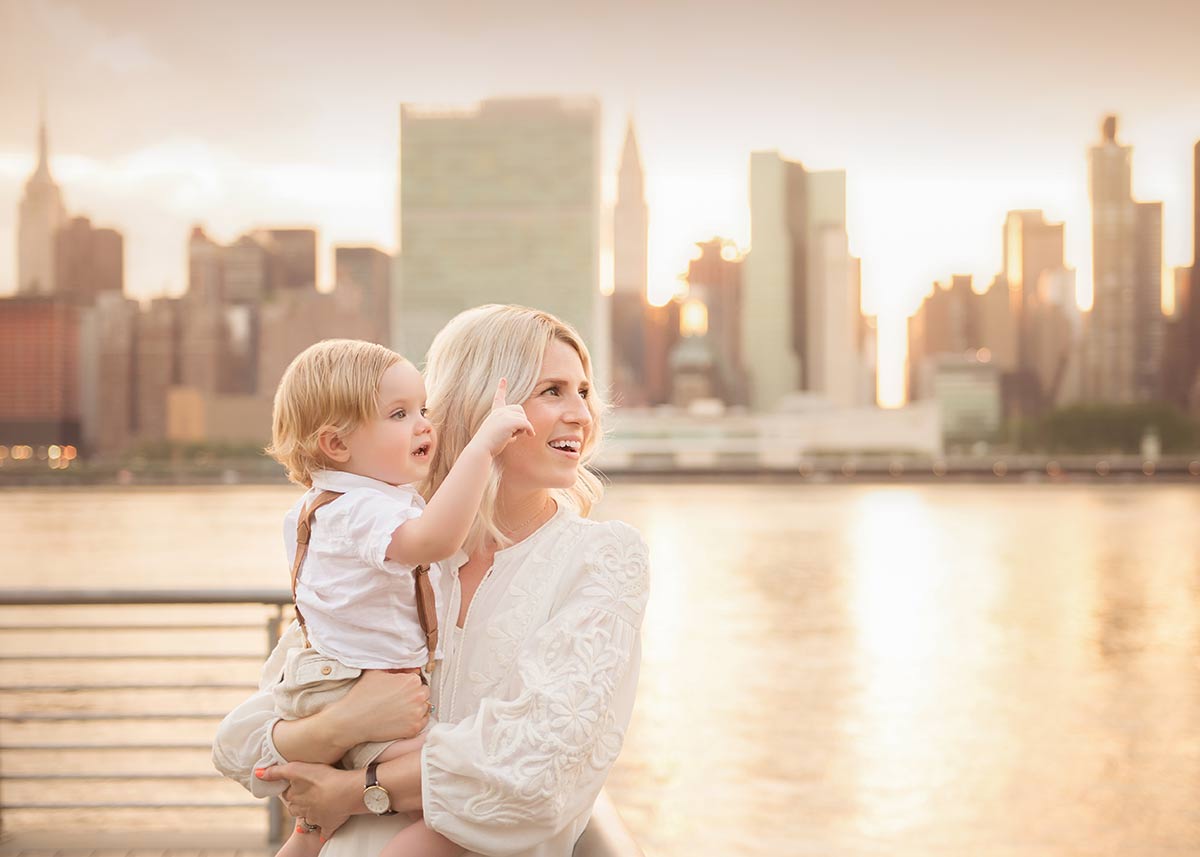 A mother holding her baby boy standing by the East River in NYC.