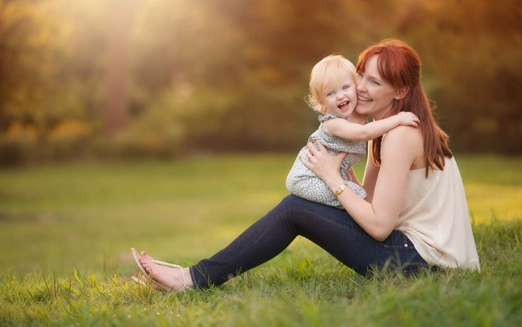 Lifestyle photo of a mother cuddling her baby girl in Central Park.