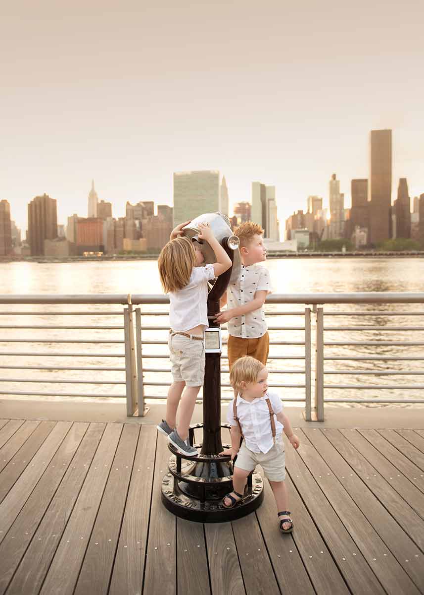 Lifestyle moment of three boys playing with a scope on a NYC waterfront.