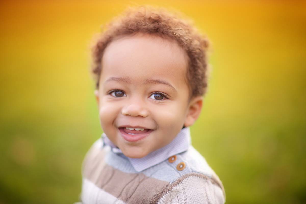 Portrait of a toddler boy in a sweater smiling.