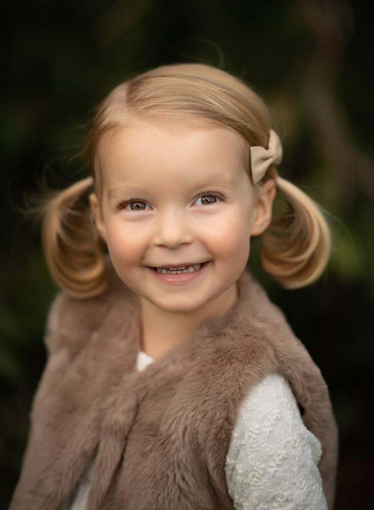 Young girl in ponytails smiling happily.