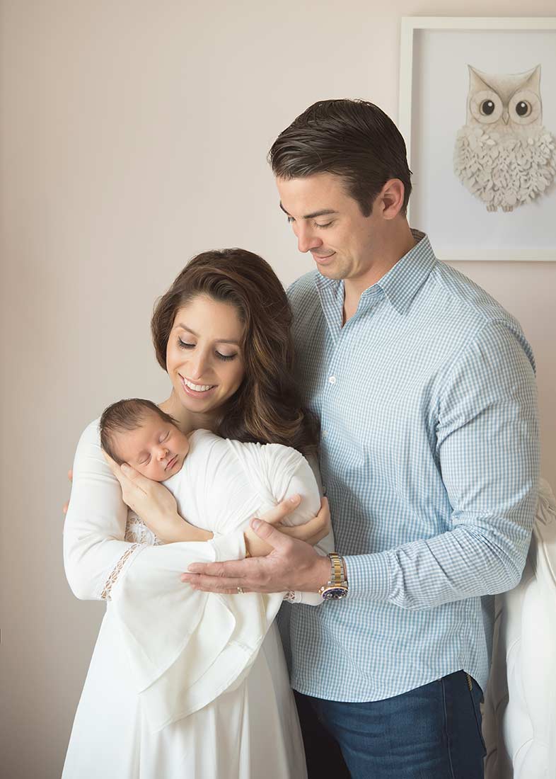 Husband and wife cradling their newborn baby in arms