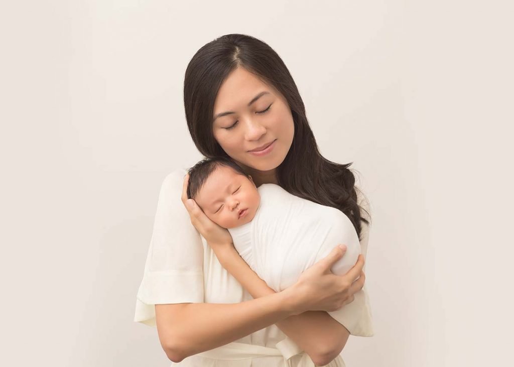 Mom holding her swaddled newborn in arms