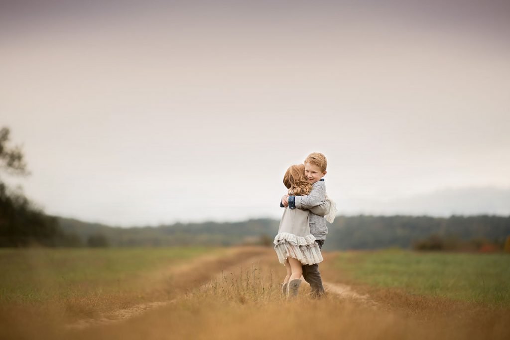 Brother hugging his sister on a dirt road