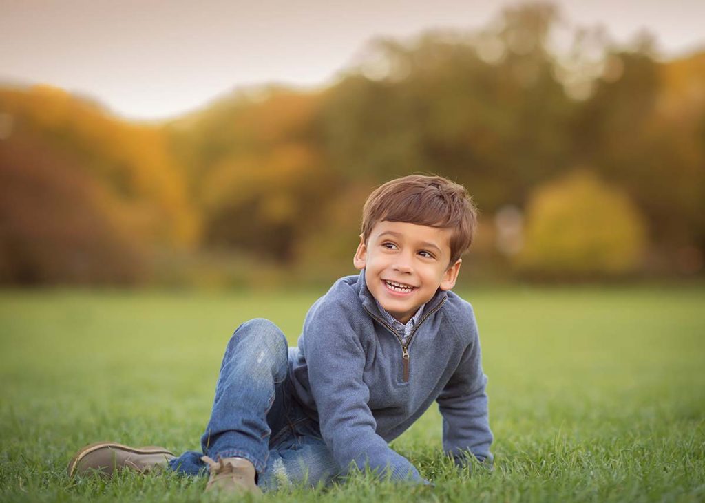 Boy in jeans smiling in grass