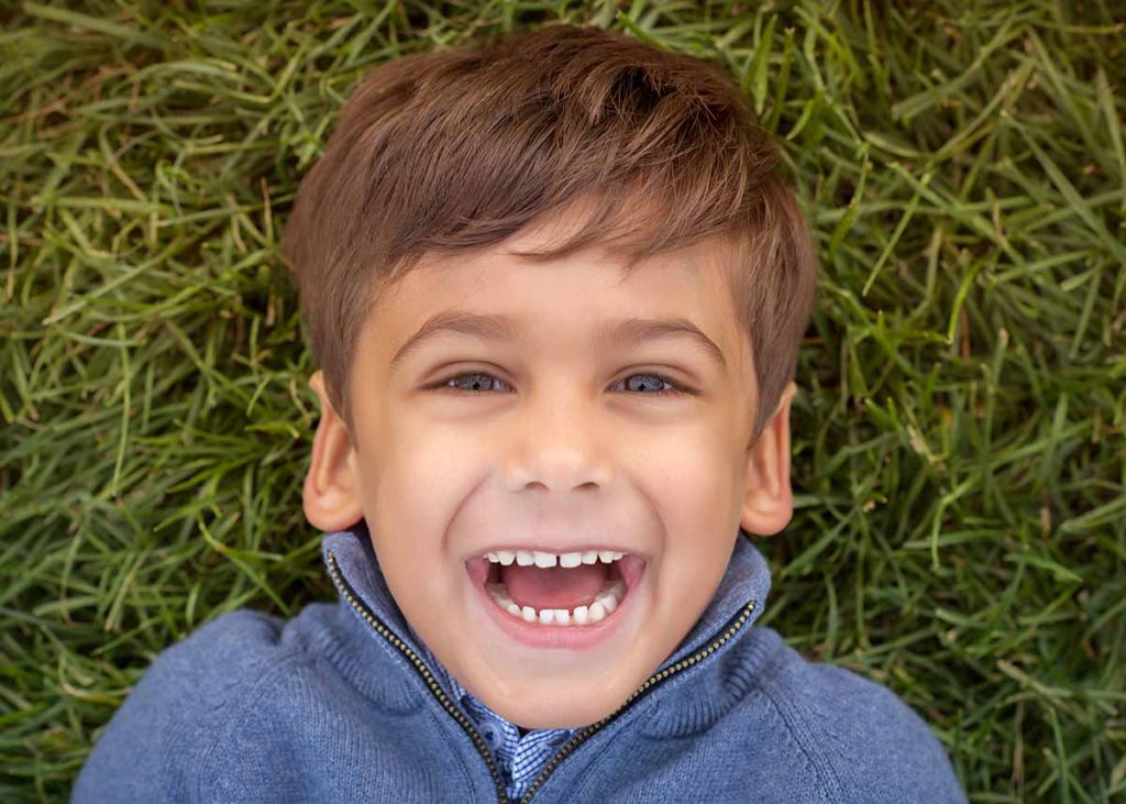 Top down view of a boy smiling in grass