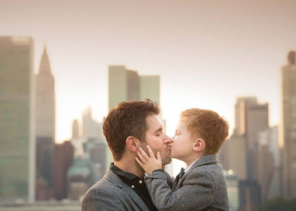 Father kissing his son with NYC skyline in the background
