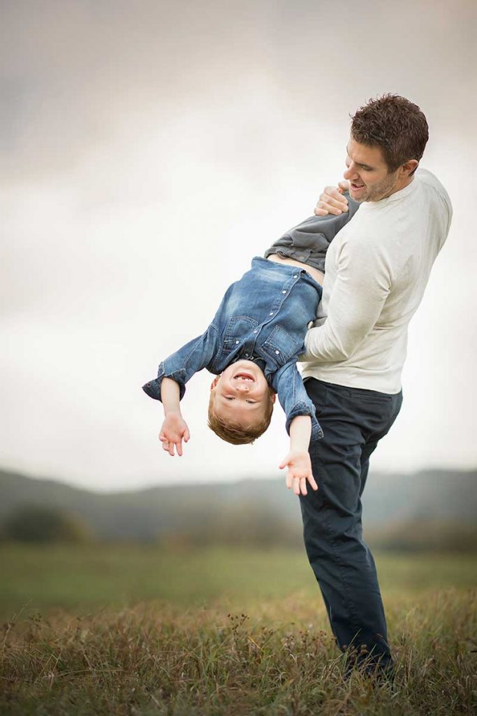 Father being playful with his son on a farm field