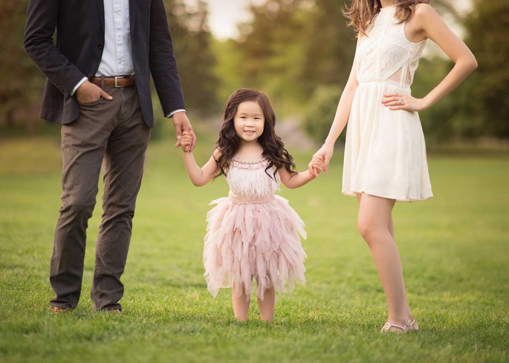 Girl wearing a tutu holding her parents' hands