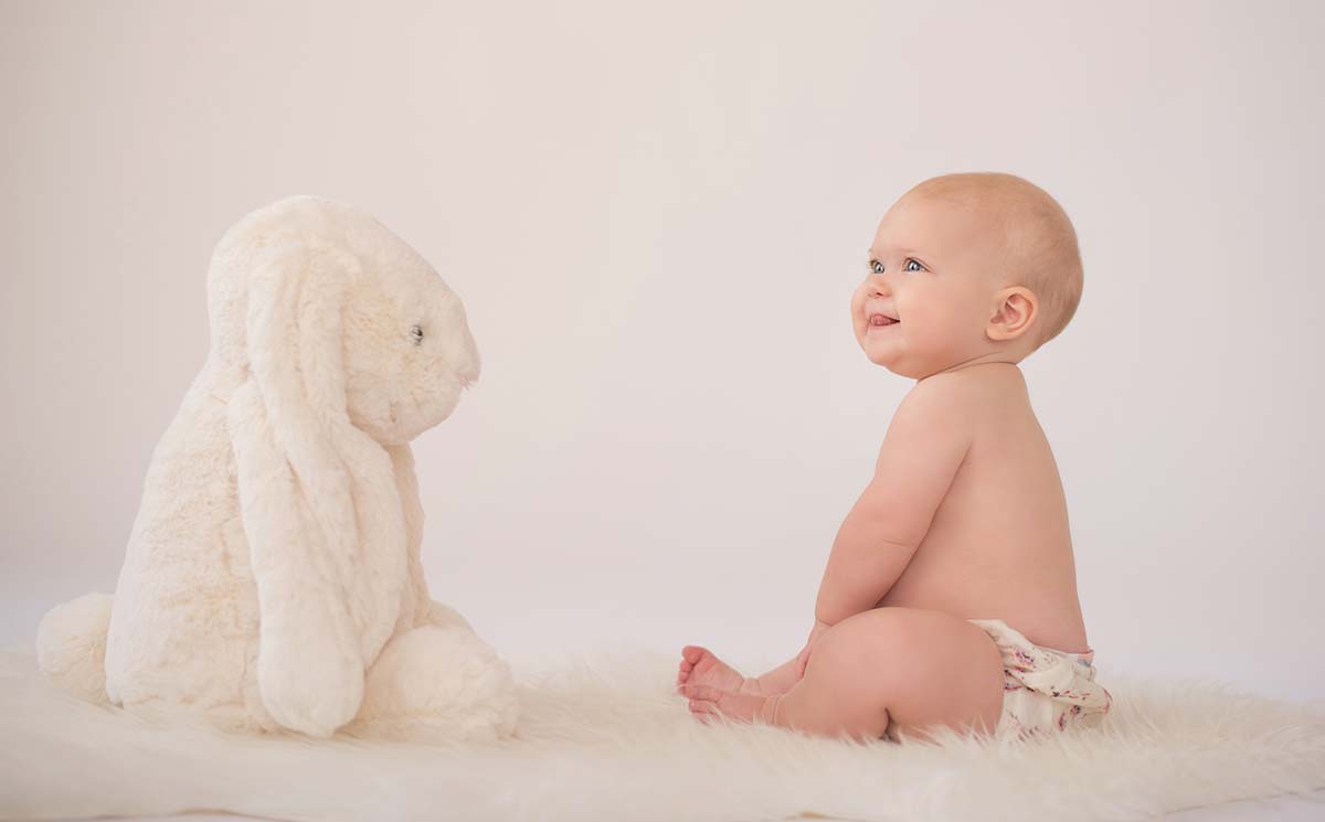 Baby in a photo studio looking at a stuffed toy