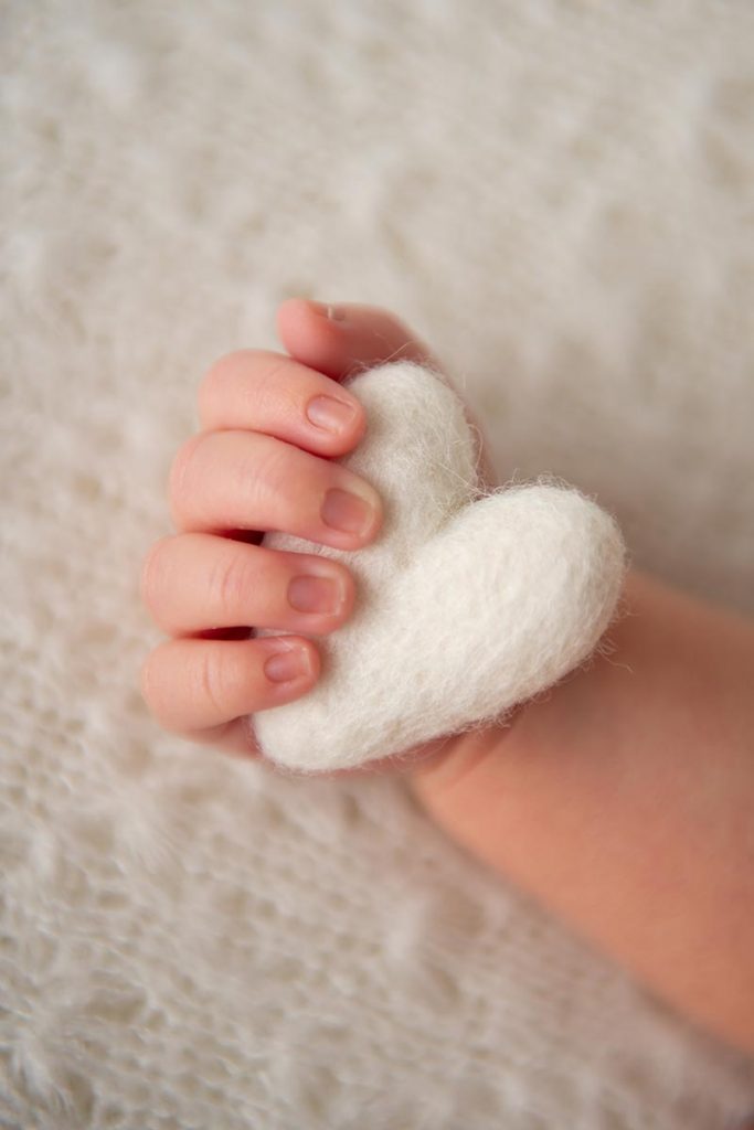 Closeup of infant's hand holding a stuffed heart