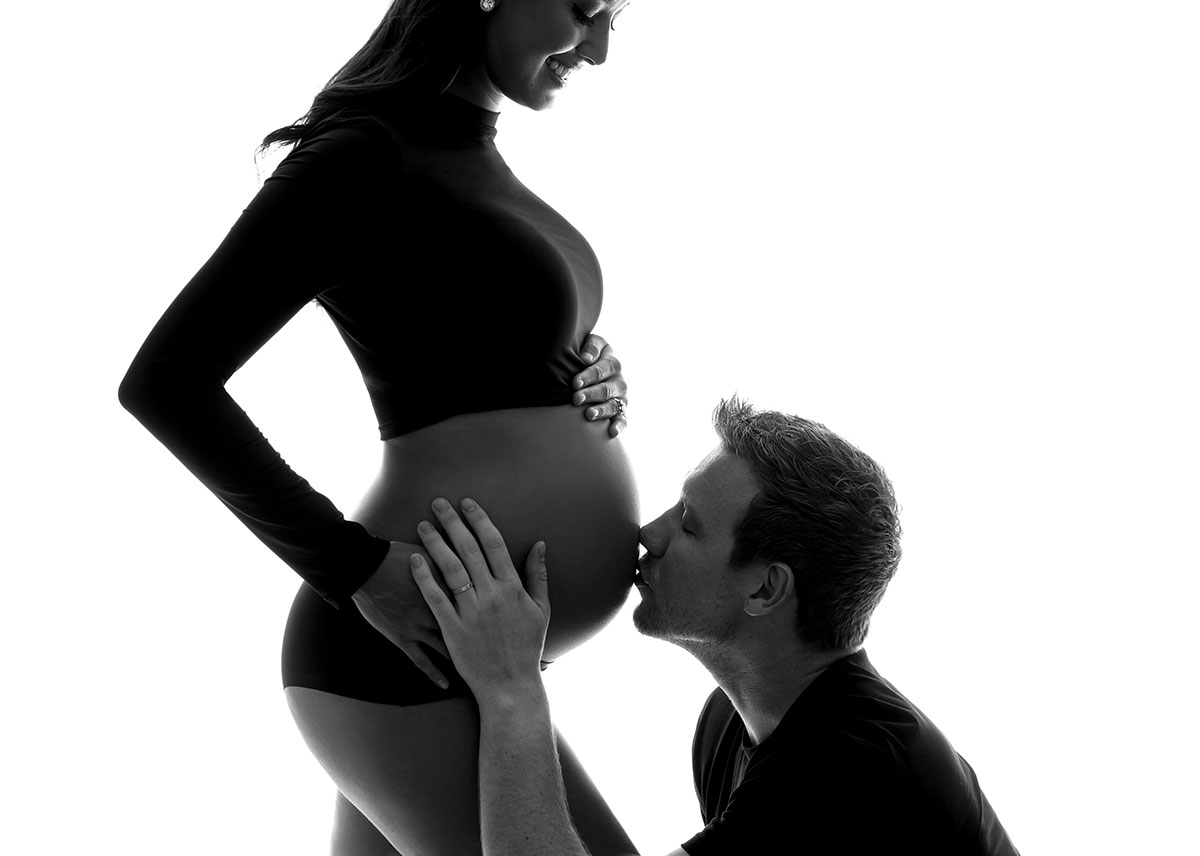 Father kissing his wife's pregnant belly