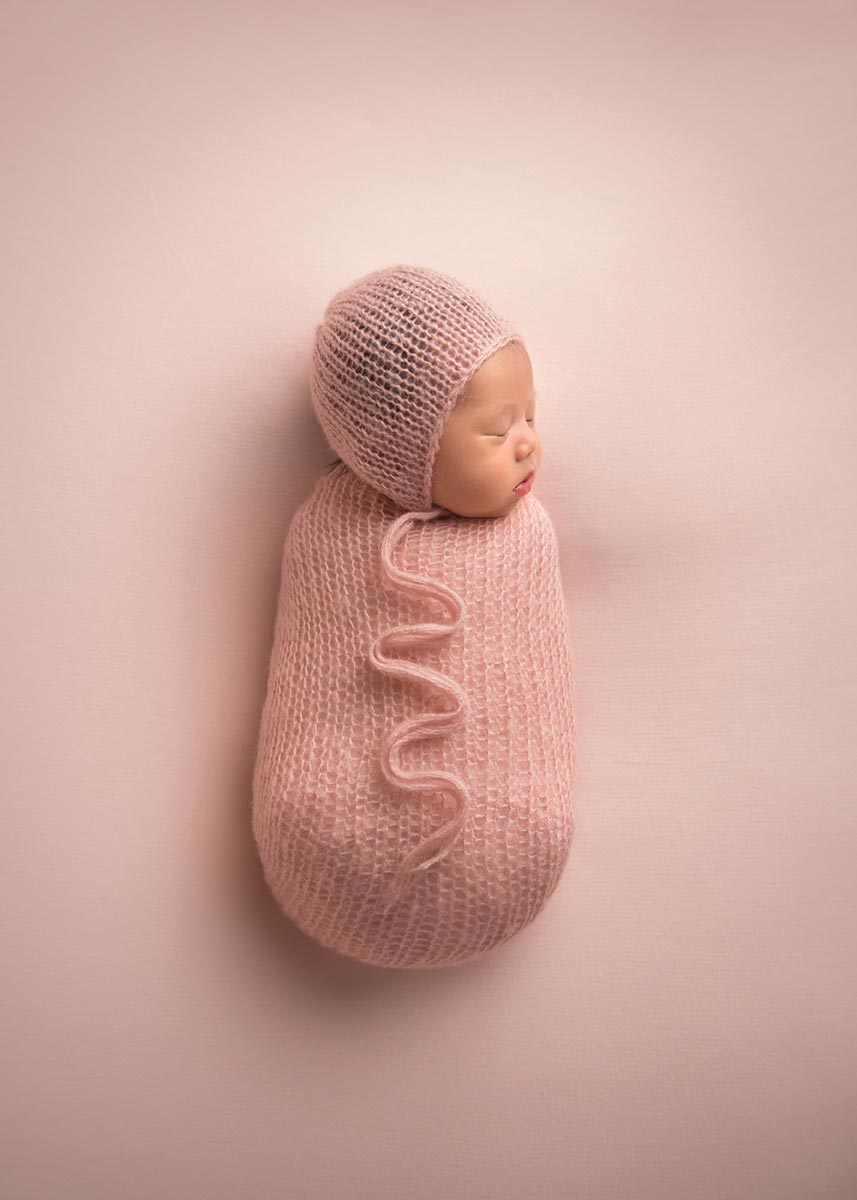 Cute baby swaddled in a pink knit