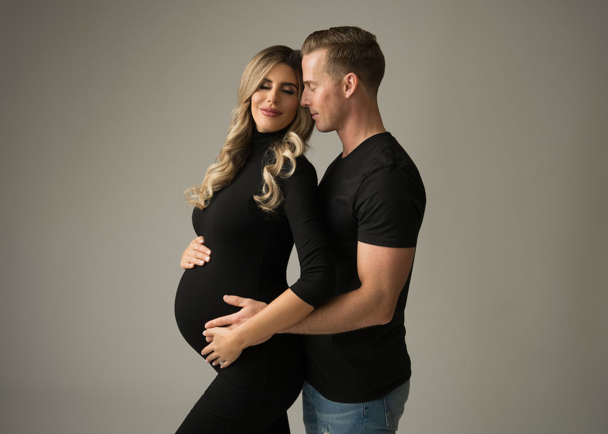 Husband and wife posing for a pregnancy photo