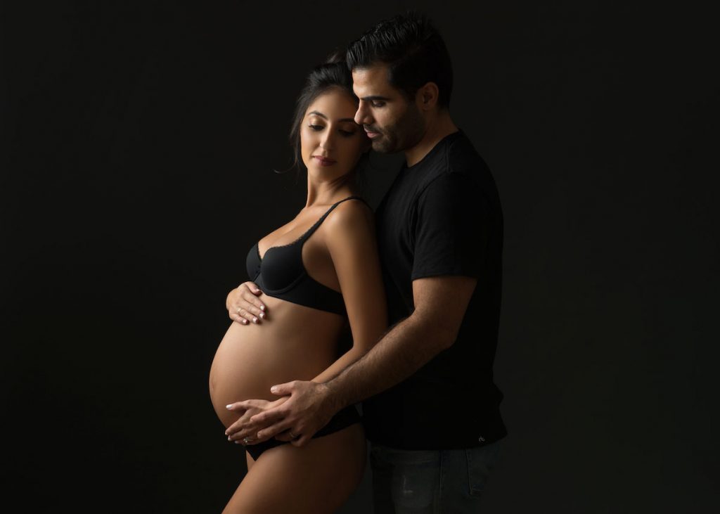 Man and wife embracing her pregnancy curves in this amazing maternity photo taken in NYC