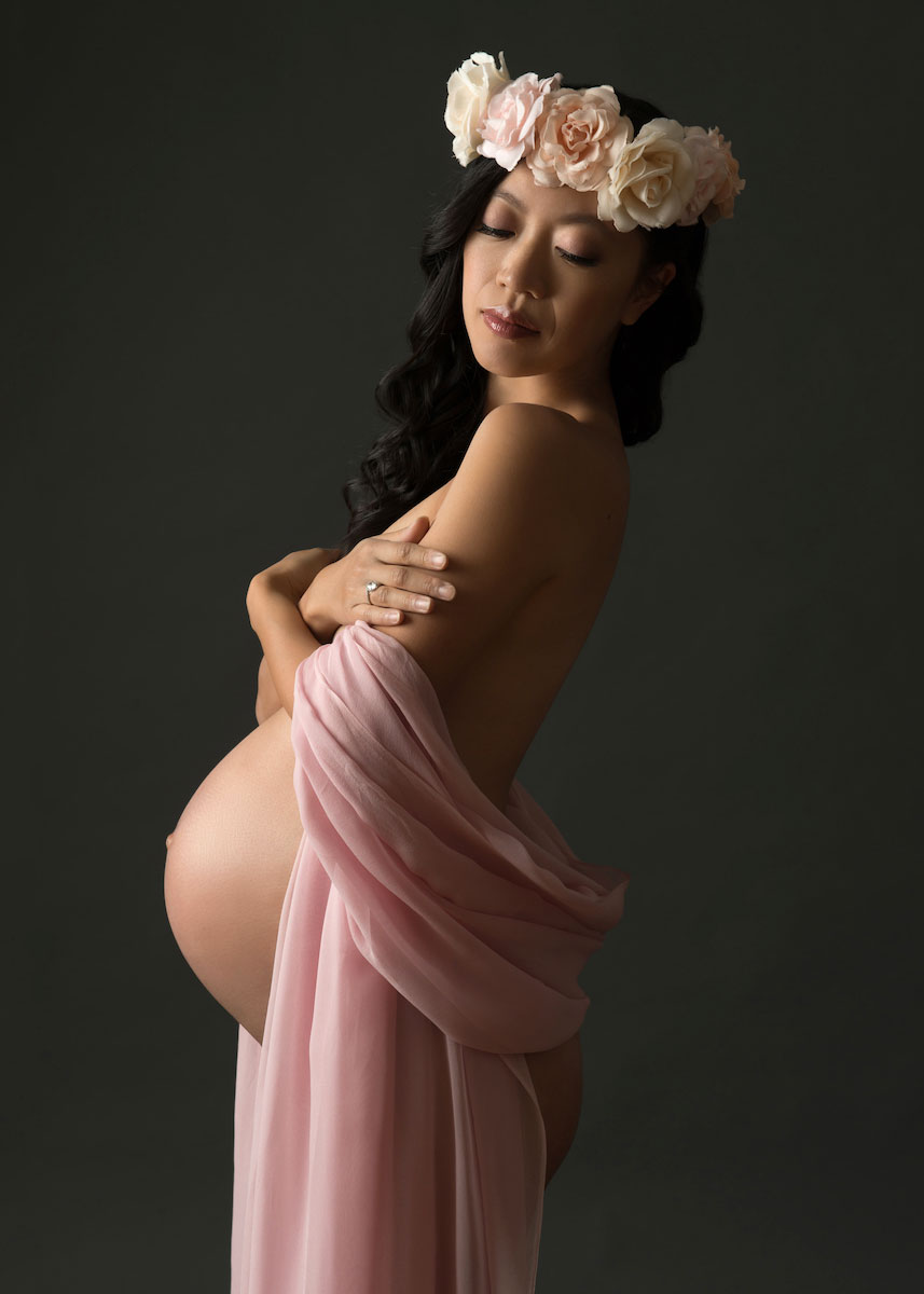 Pregnant woman wearing a rose headband and a pink drape
