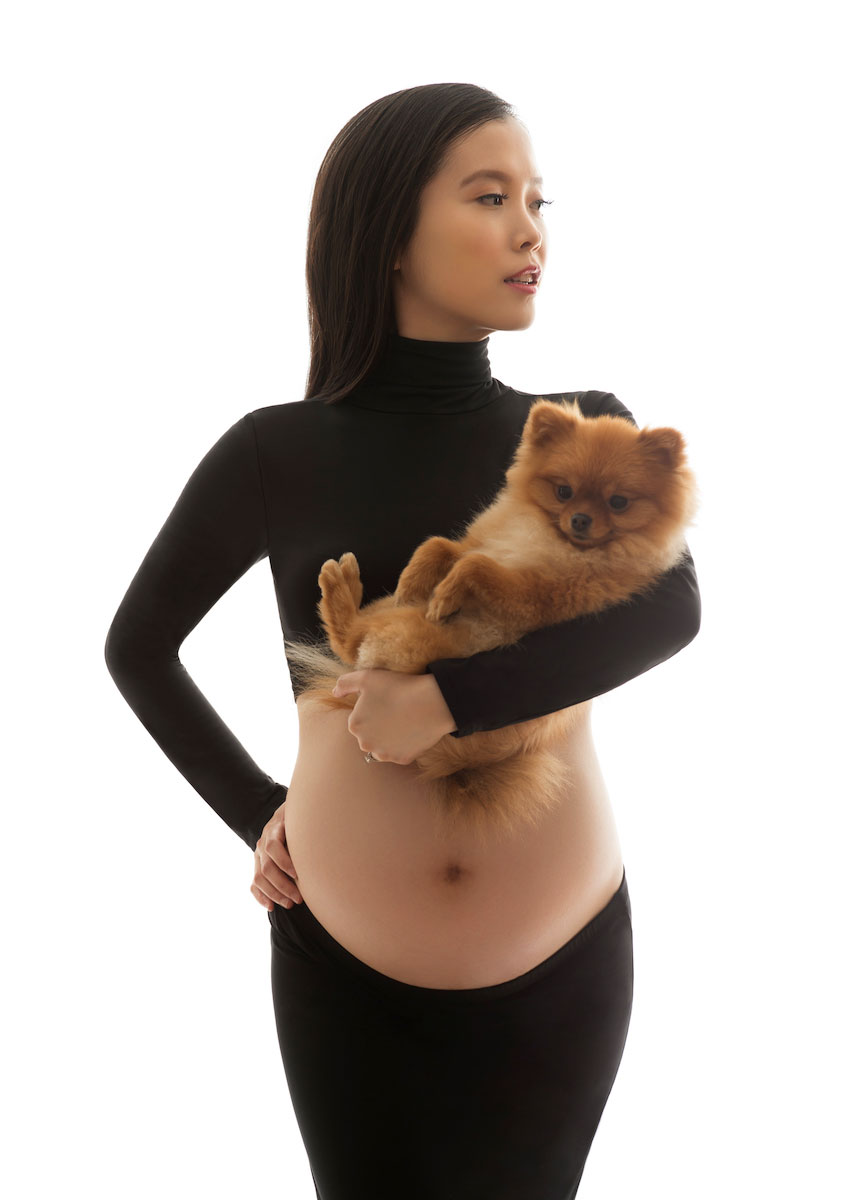 Pregnant woman in a black croptop holding a dog