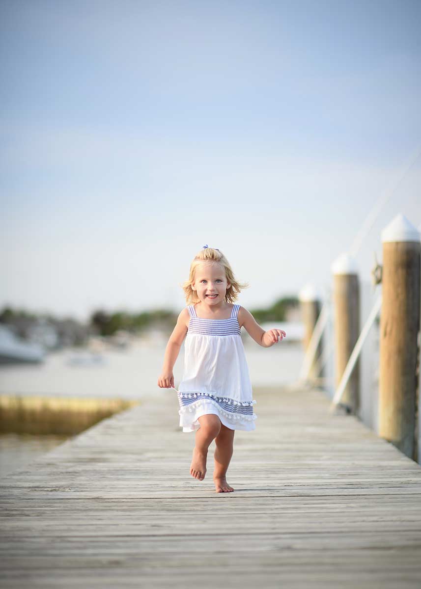 A happy girl running down a dock at a marina in the Hamptons