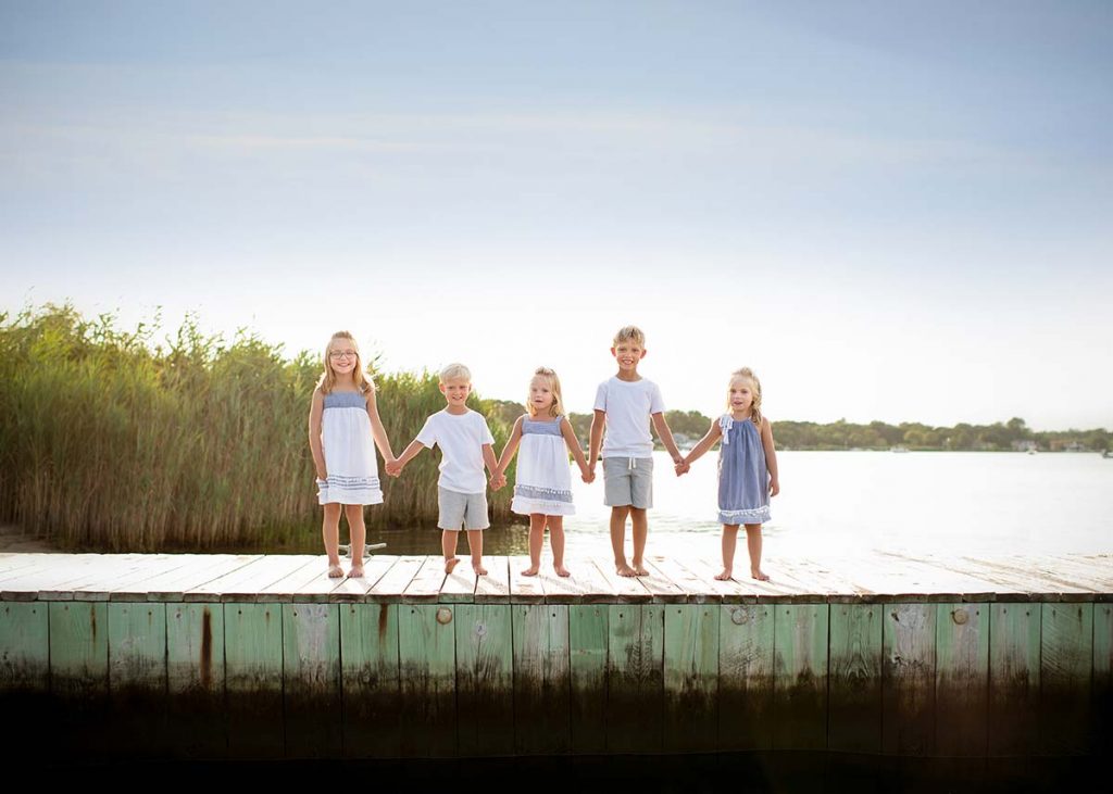 Children holding hands on a dock in the Hamptons