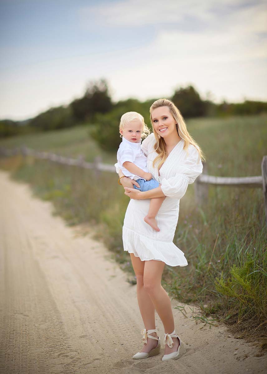A stylish mom holding her son on a sandy path near Hamptons