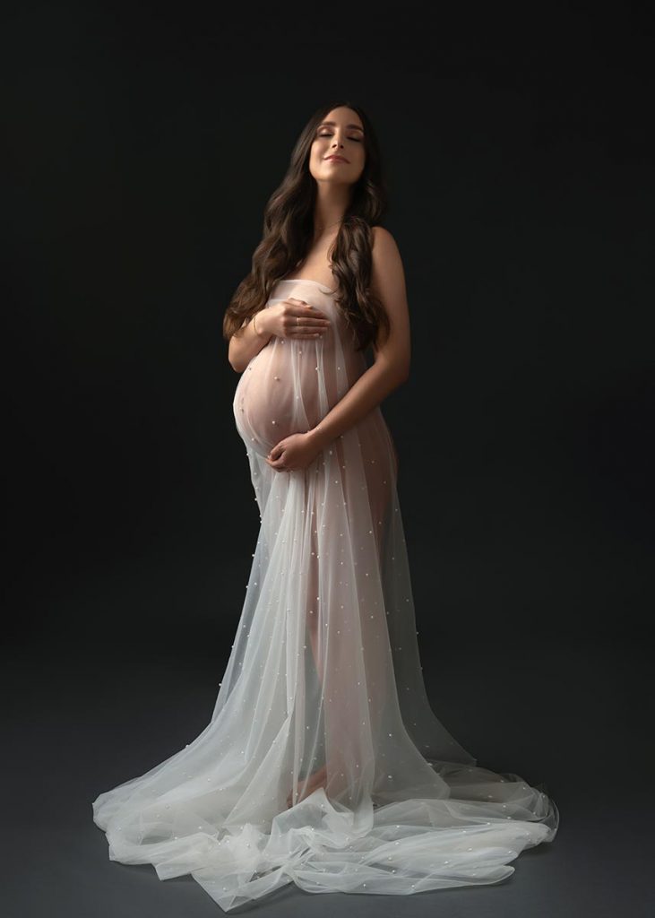 Opaque veil draped around the belly of a pregnant woman