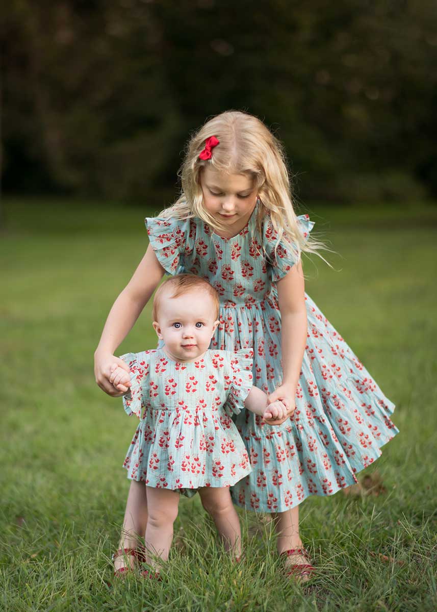 Two little sisters in matching dresses holding hands in NYC's Central Park