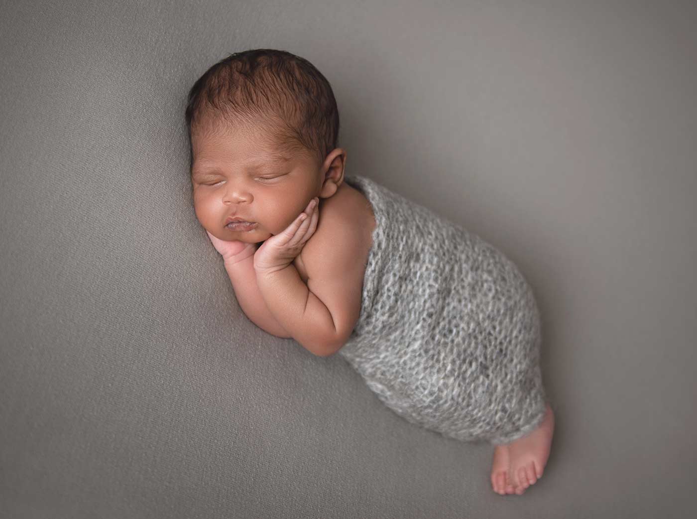 baby portrait sleeping with hands on cheeks in knit grey swaddle