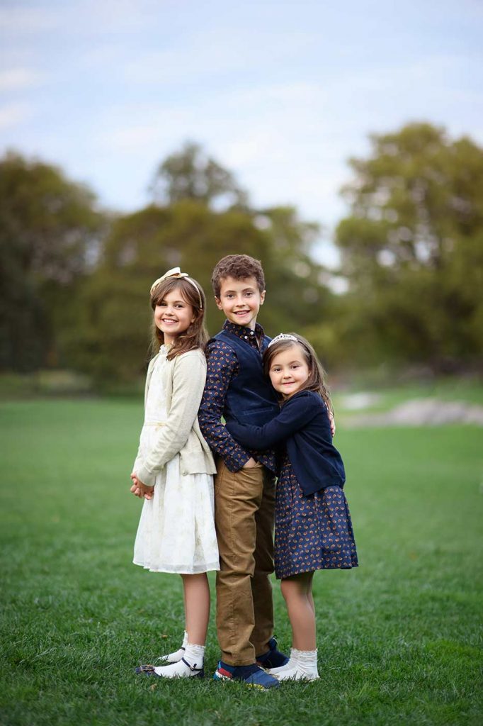 Brother and his sisters posing for a photo in Central Park's meadow