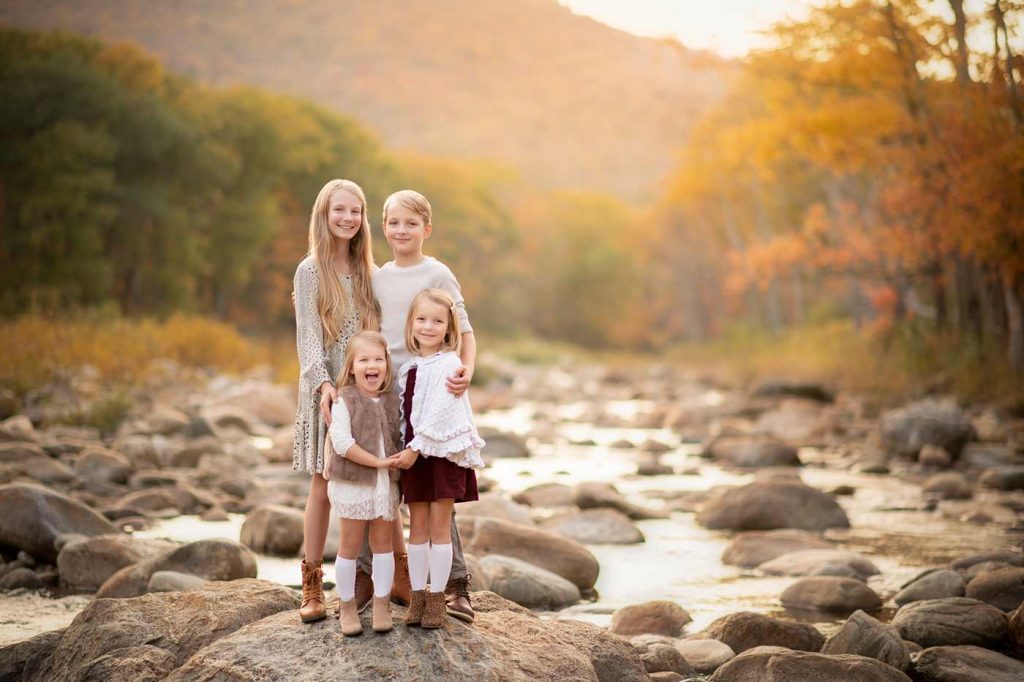 Siblings standing near a river during autumn sunset