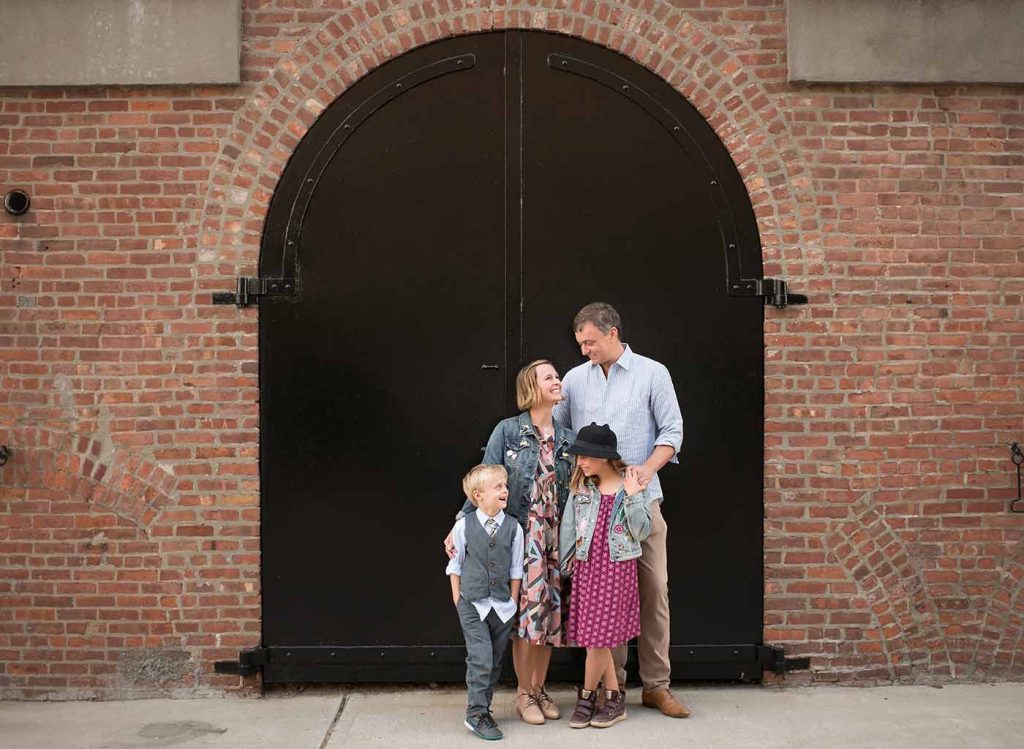 Modern NYC family standing near an iron gate in Brooklyn's industrial section