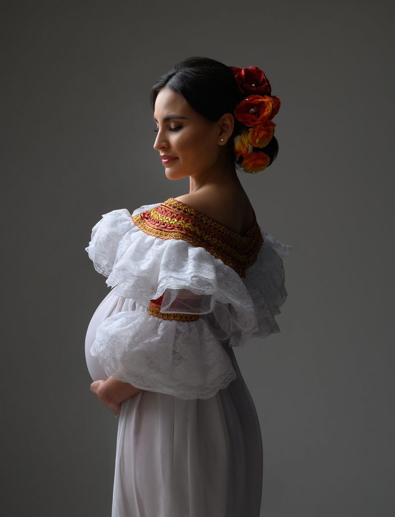 maternity portrait with colorful flowers and traditional Spanish lace ruffle dress