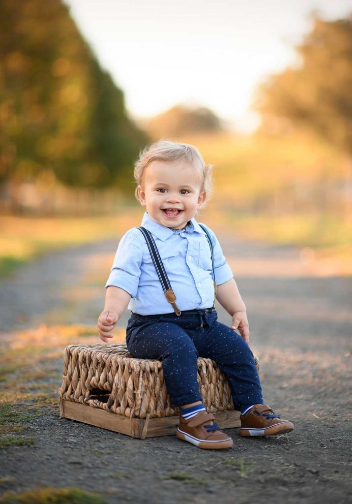 Happy toddler sitting on a basket at a farm and smiling