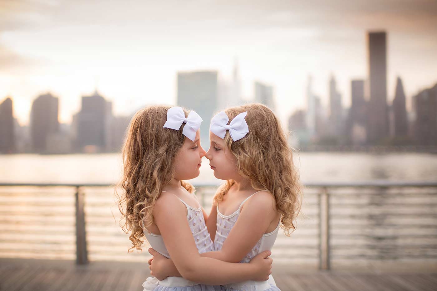 Two sisters nose kissing with NYC skyline as backdrop