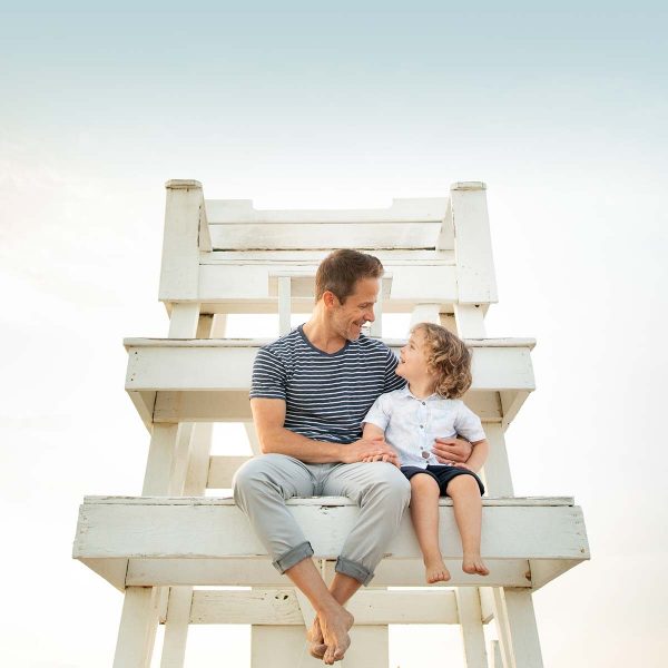 Father and son sitting on lifeguard tower in the Hamptons