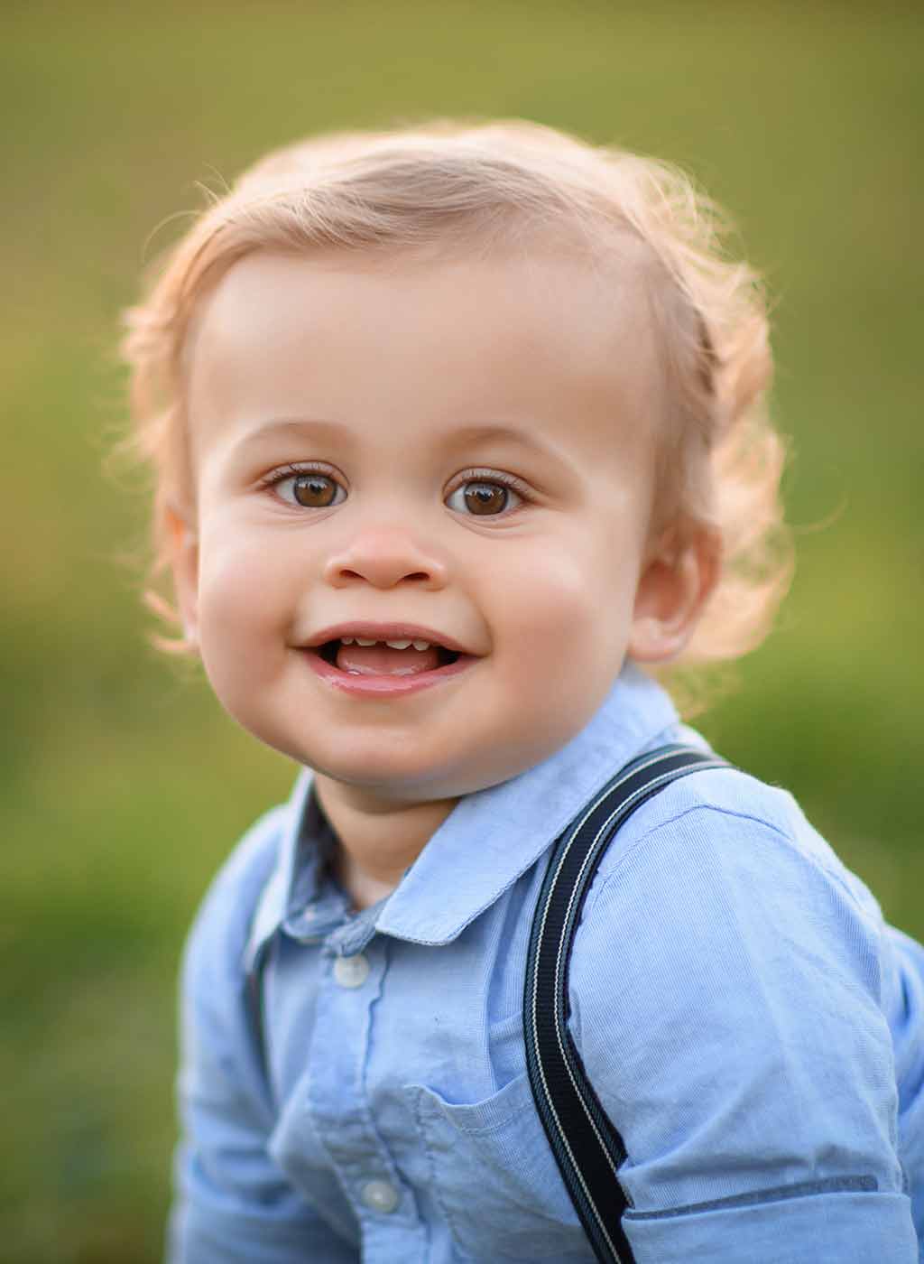 Closeup of a toddler boy smiling in a grass field