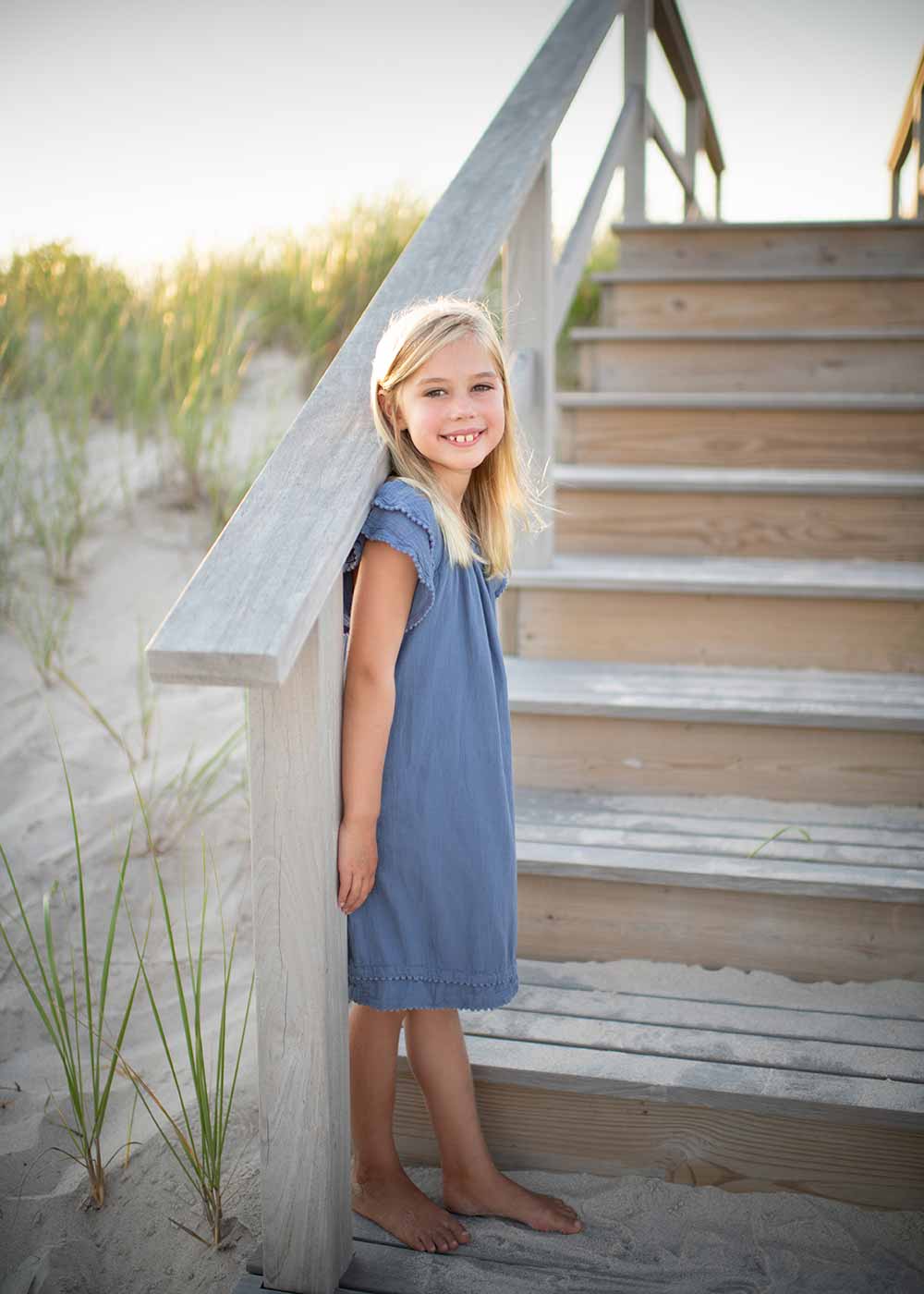Young girl in a blue dress standing on a beach near Southampton