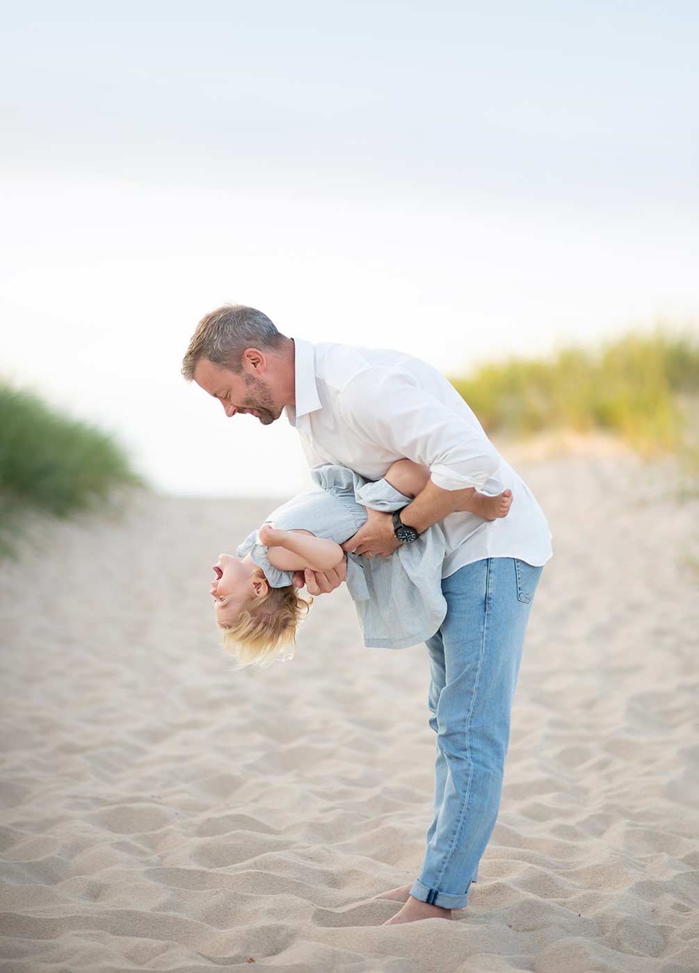 Father sharing a playful moment with his daughter on a beach near Westhampton, NY