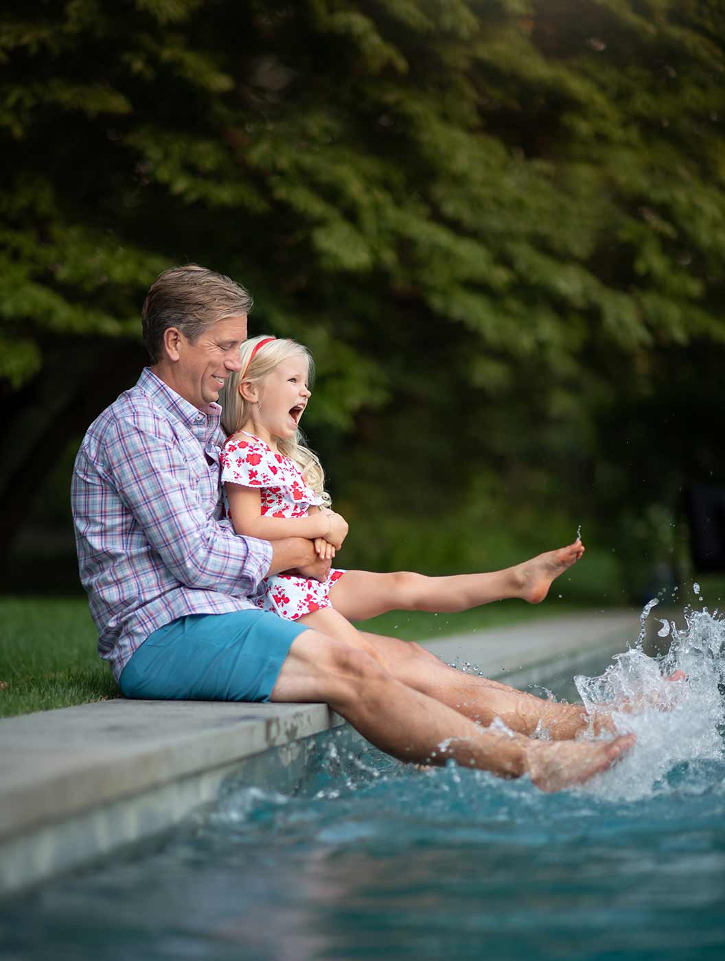 Father and his daughter kicking water in a swimming pool