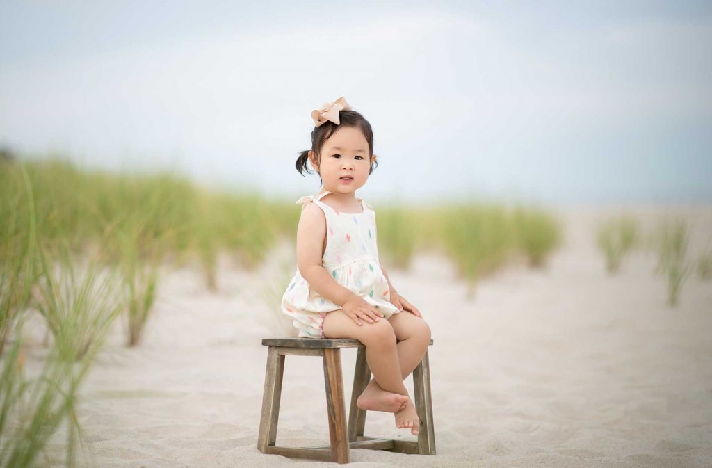 girl-bench-beach Toddler sitting on a sandy beach in East Hampton, NY