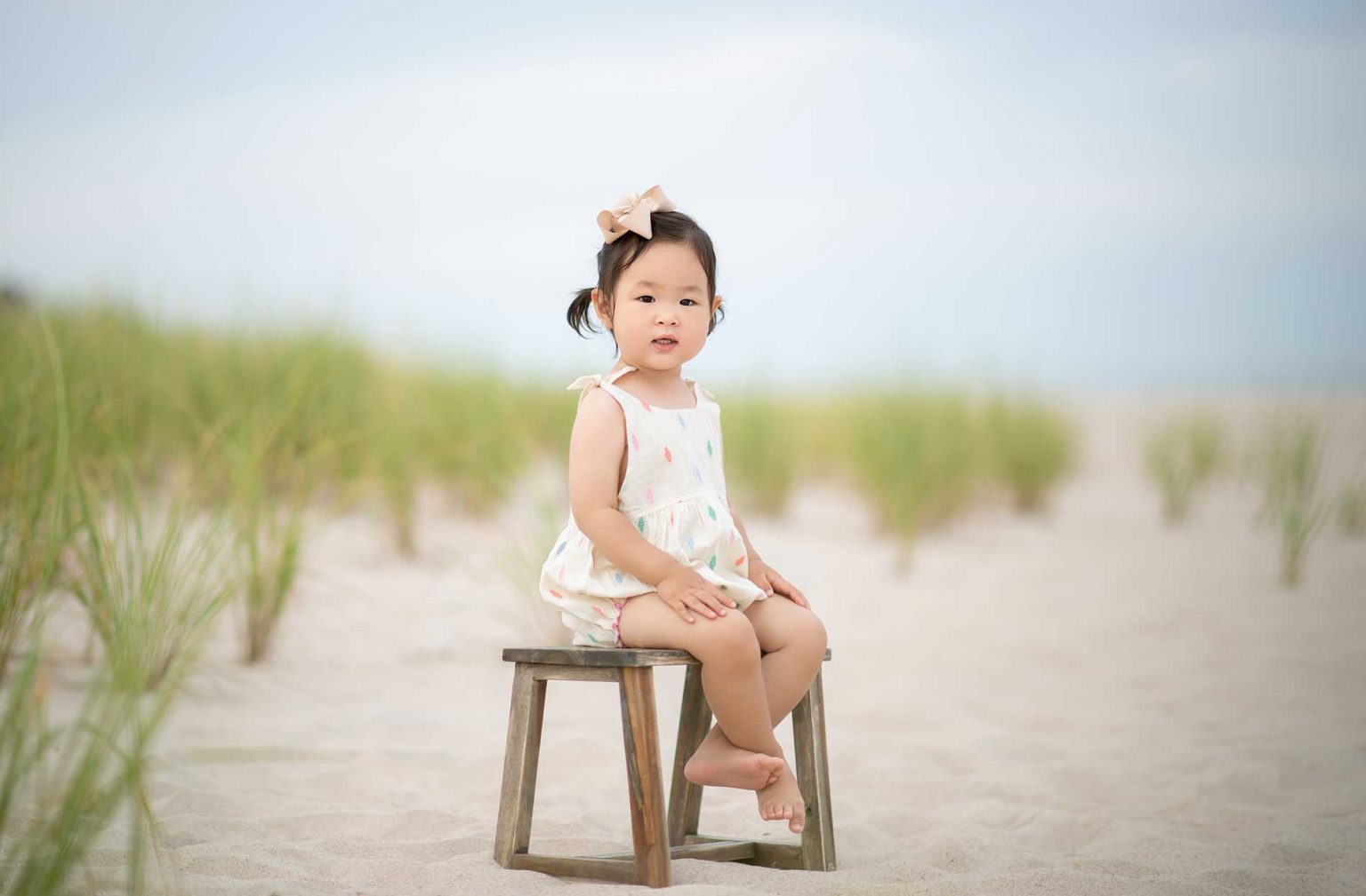 Toddler sitting on a sandy beach in East Hampton, NY