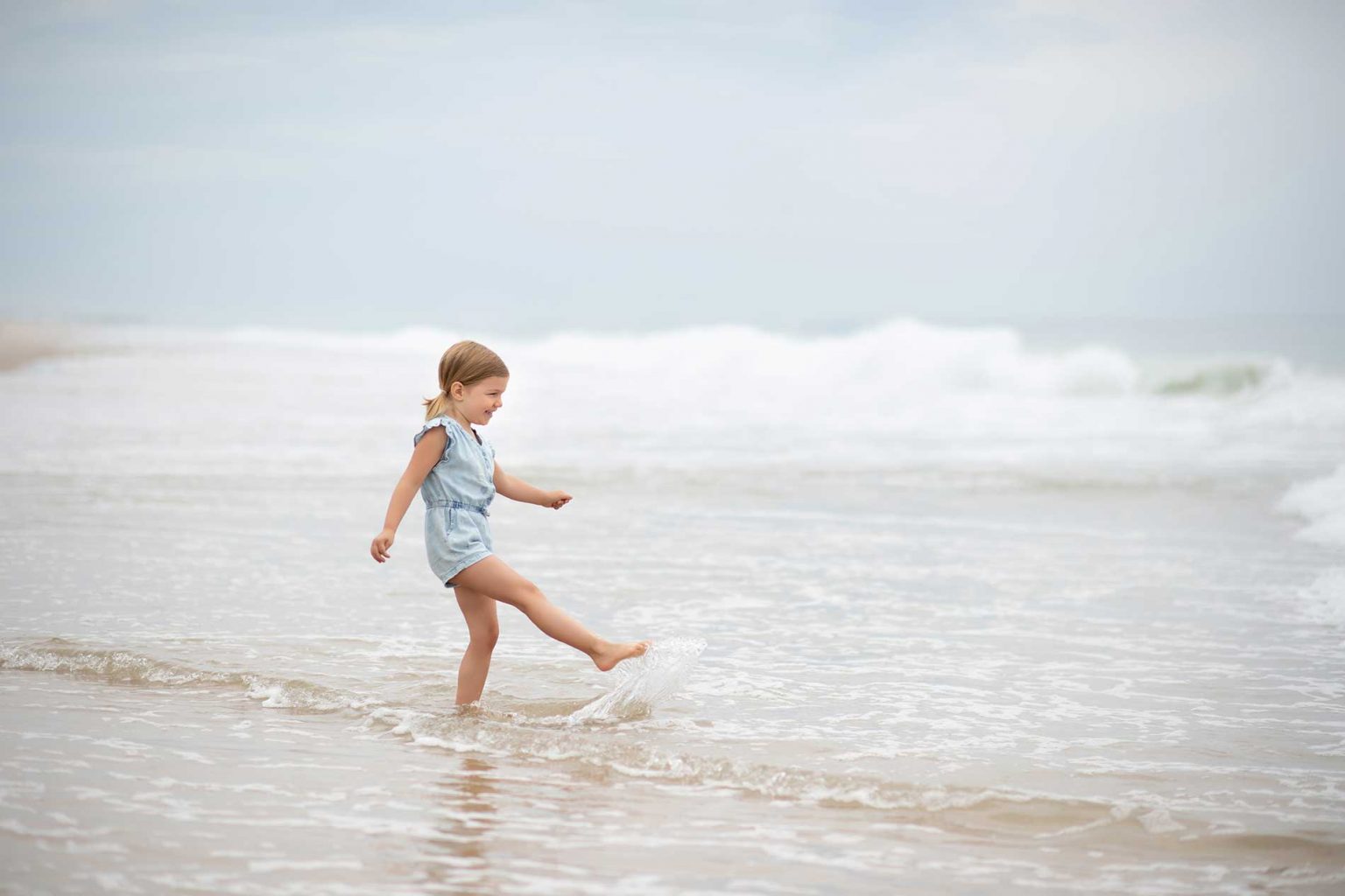 Toddler kicking water at a beach in Bridgehampton NY