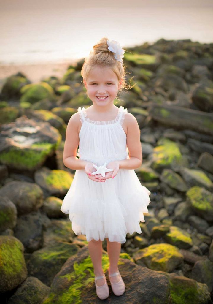 girl-tutu-surf Youg girl in a white tutu holding a starfish on a beach