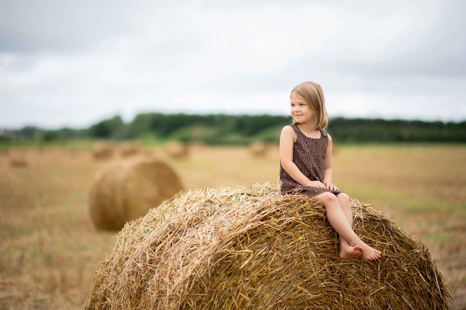 A girl sitting on rolled hay in East Hampton, NY