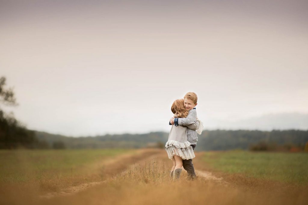 siblings-hugging-dirt-road Brother and sister hugging each other on a farm road in Sag Harbor NY