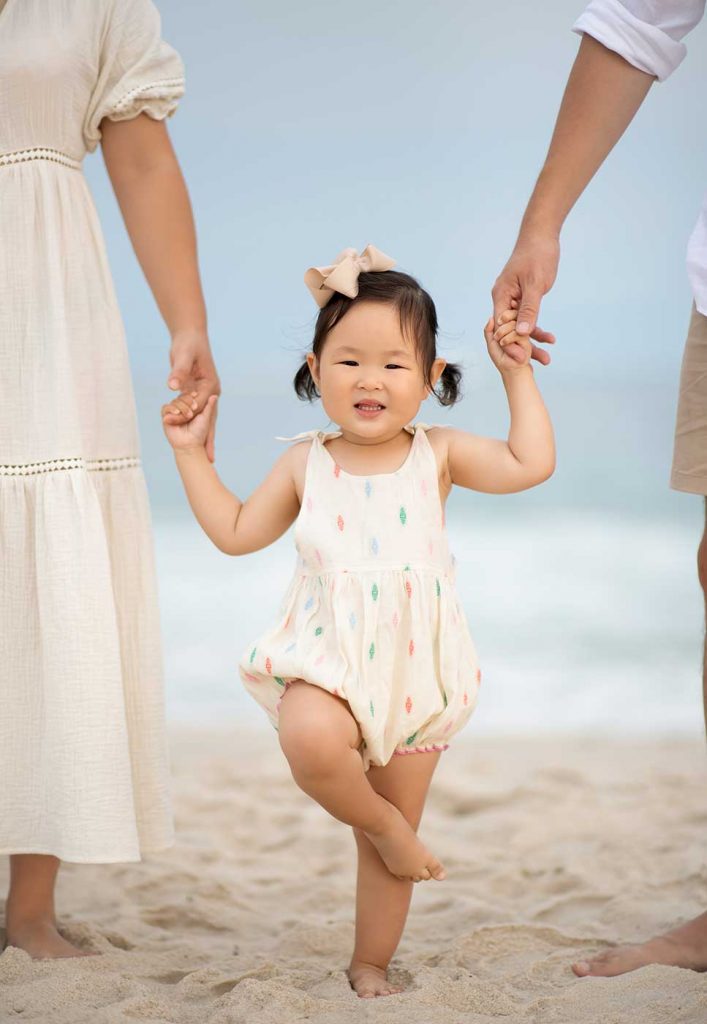smiling-girl-mom-dad Happy girl with Mom and Dad standing in the sand